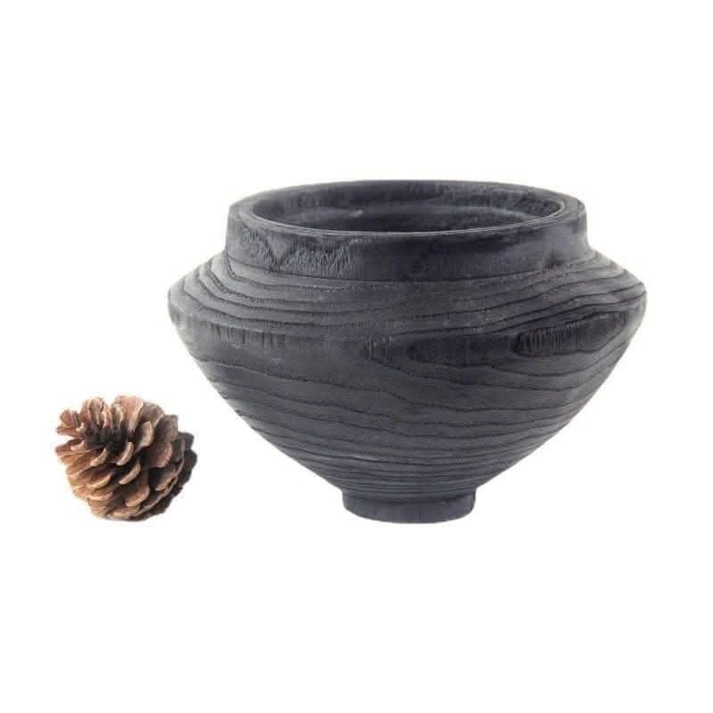 Dark wood handmade black bowl with visible grain, shown with a pine cone.